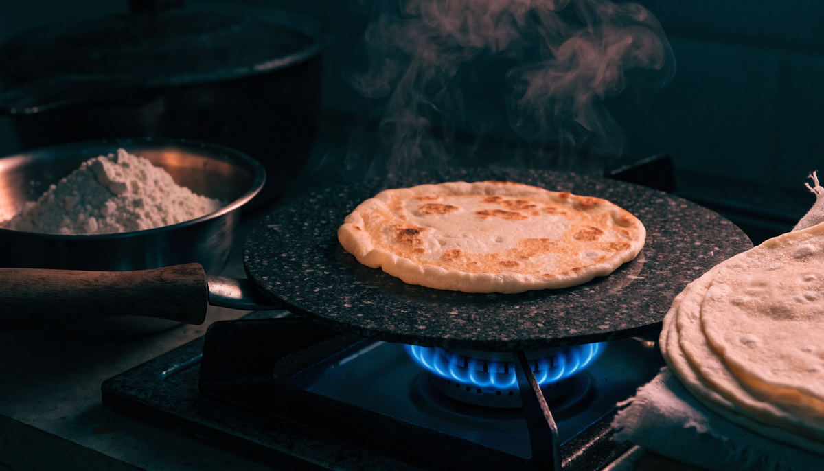Roti puffing on a black granite non-stick tawa on a gas flame
